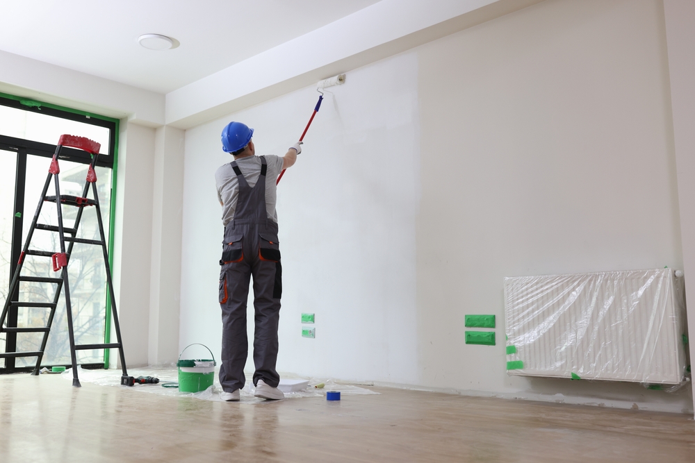 Een spons wordt gebruikt om een reinigingsmengsel op de muur aan te brengen na het verwijderen van glasvezelbehang. Het mengsel helpt bij het verwijderen van lijmresten en voorbereiden van de muur voor verdere verbeteringen.