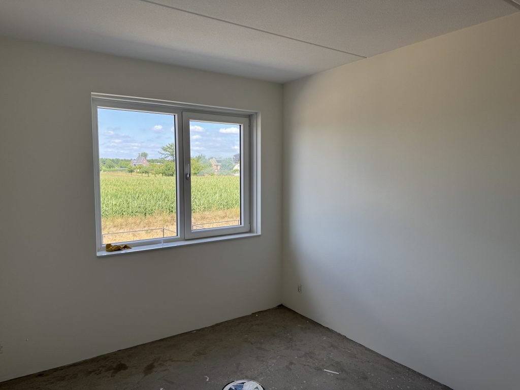 Lege nieuwbouwkamer met gladde, lichte wanden en een raam