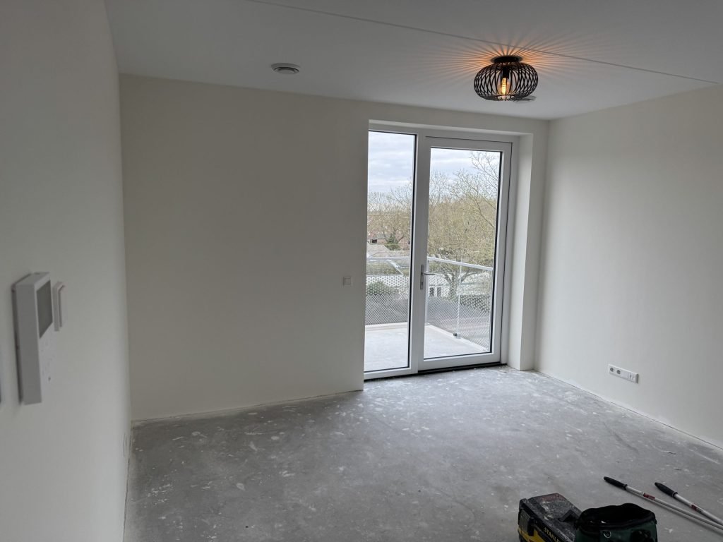 Lege nieuwbouwkamer met openslaande deuren, kort na de oplevering